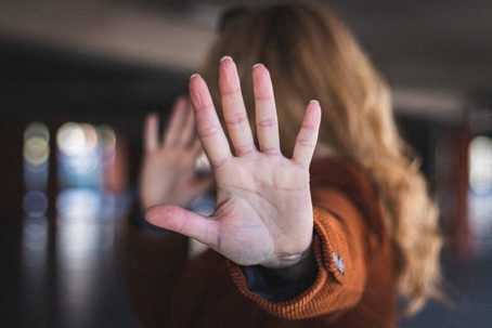Person raising hand to block workplace harassment