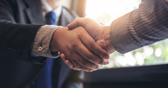 Two men shaking hands after meeting at Nichols Kaster, PLLP