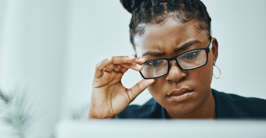Young black businesswoman frowning while using a laptop