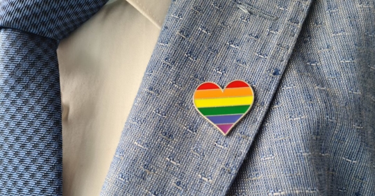 Male employee wearing a business suit with a rainbow heart on his lapel