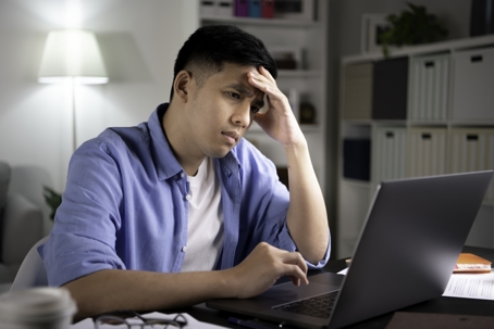 troubled man checking computer at home