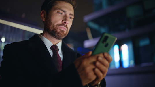 serious man reading something on his phone at night
